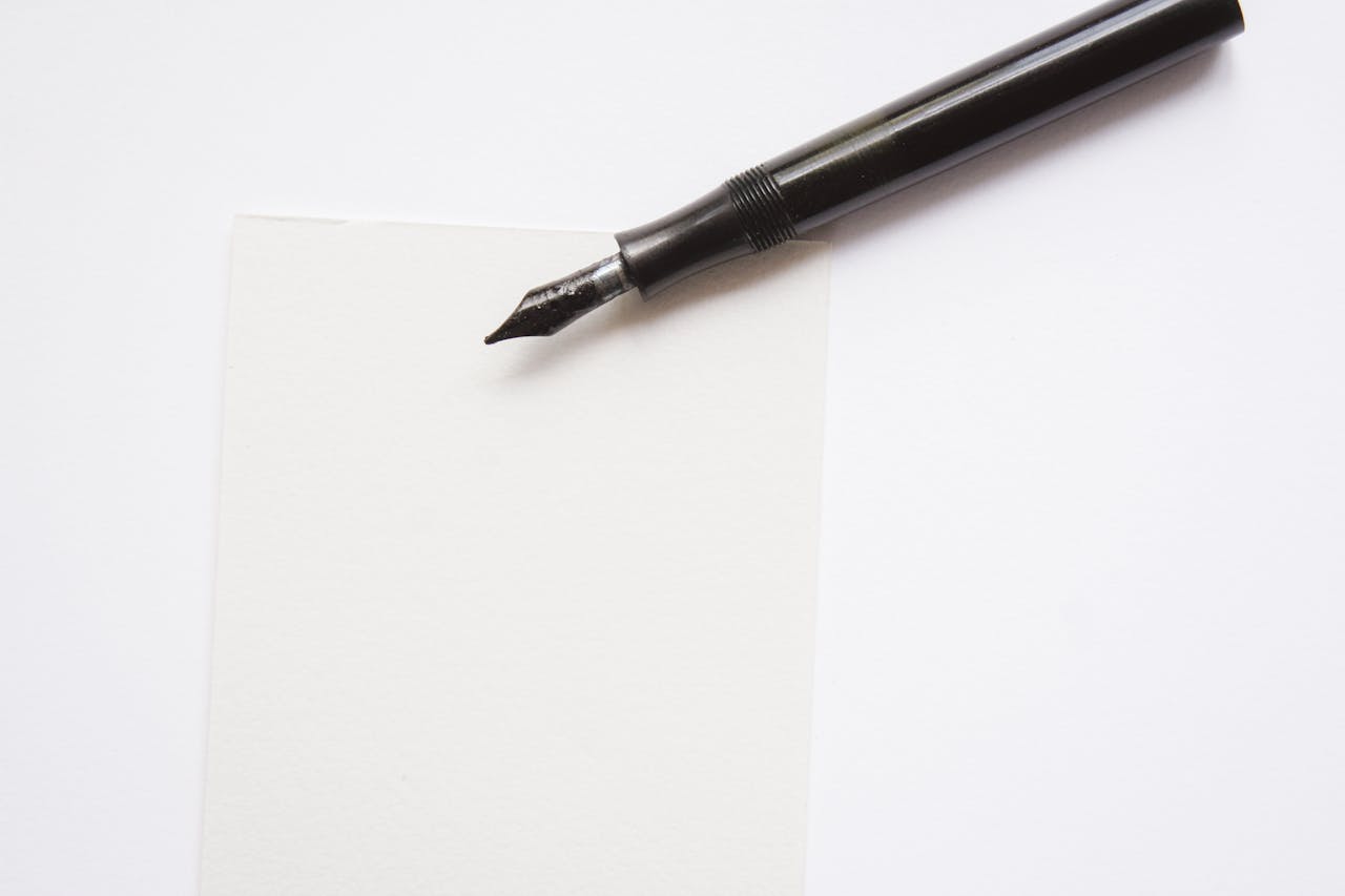 A close-up image of an elegant fountain pen resting on blank white paper, perfect for writing themes.